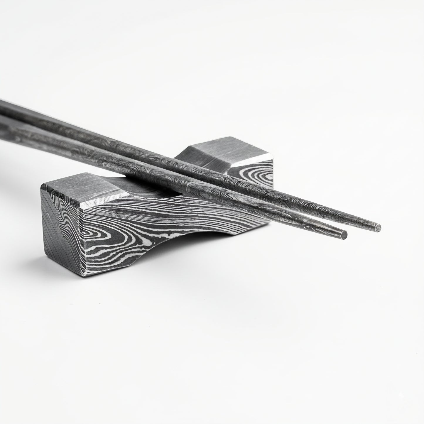 Decorative metal chopstick rest with intricate patterns on a white background