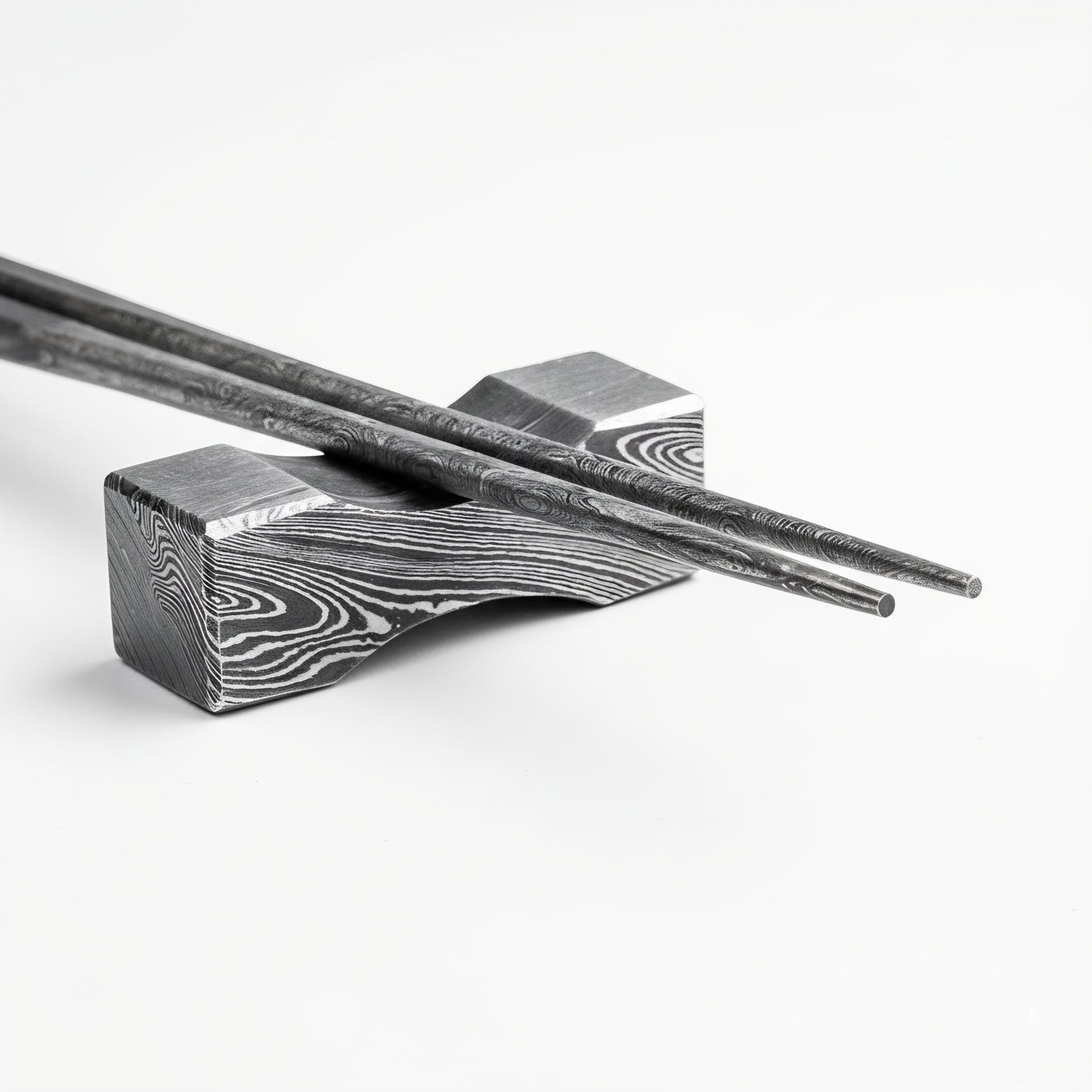 Decorative metal chopstick rest with intricate patterns on a white background