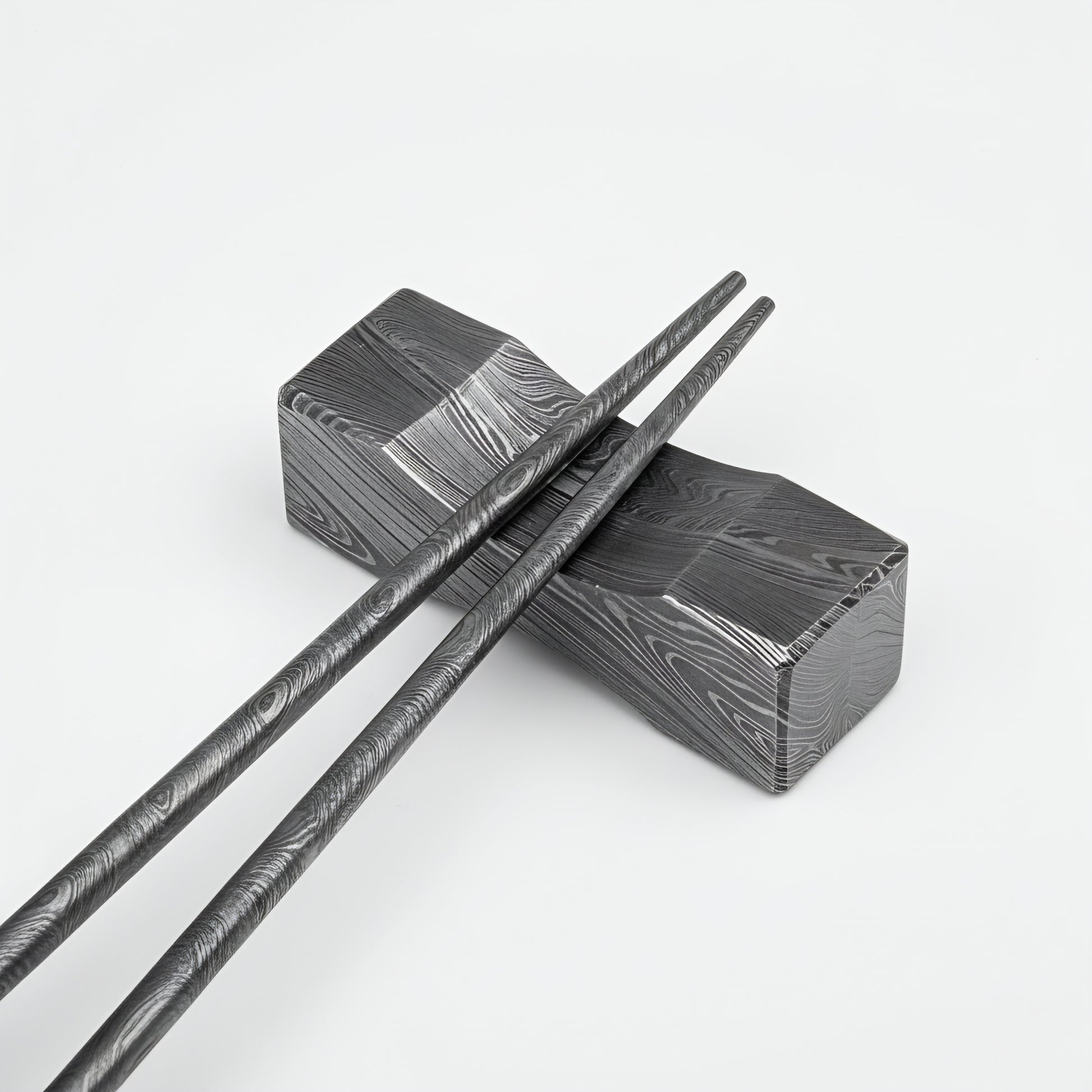 Black and silver patterned chopsticks on a matching black and silver box against a white background