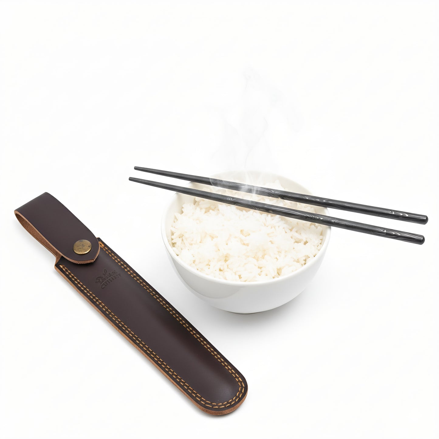Black chopsticks on a white bowl of rice with a brown leather case on a white background