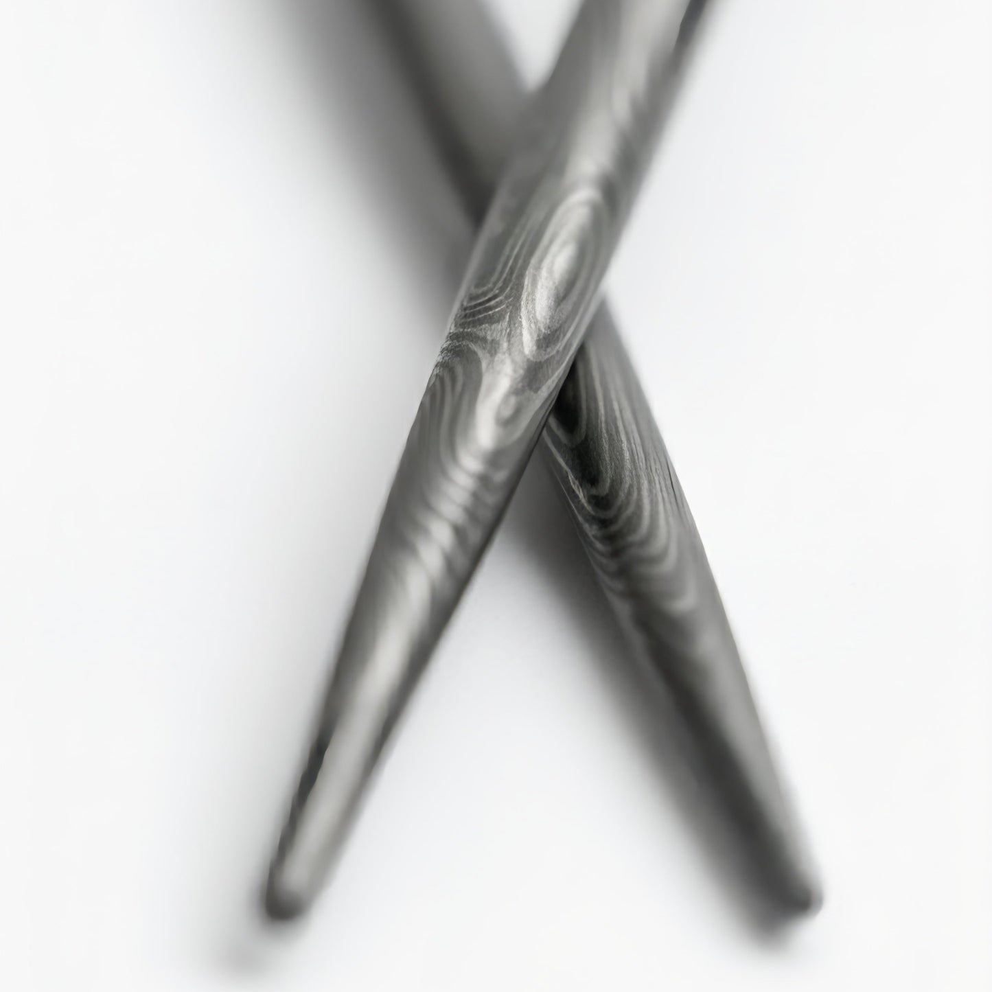 Close-up of two crossed damascus chopsticks