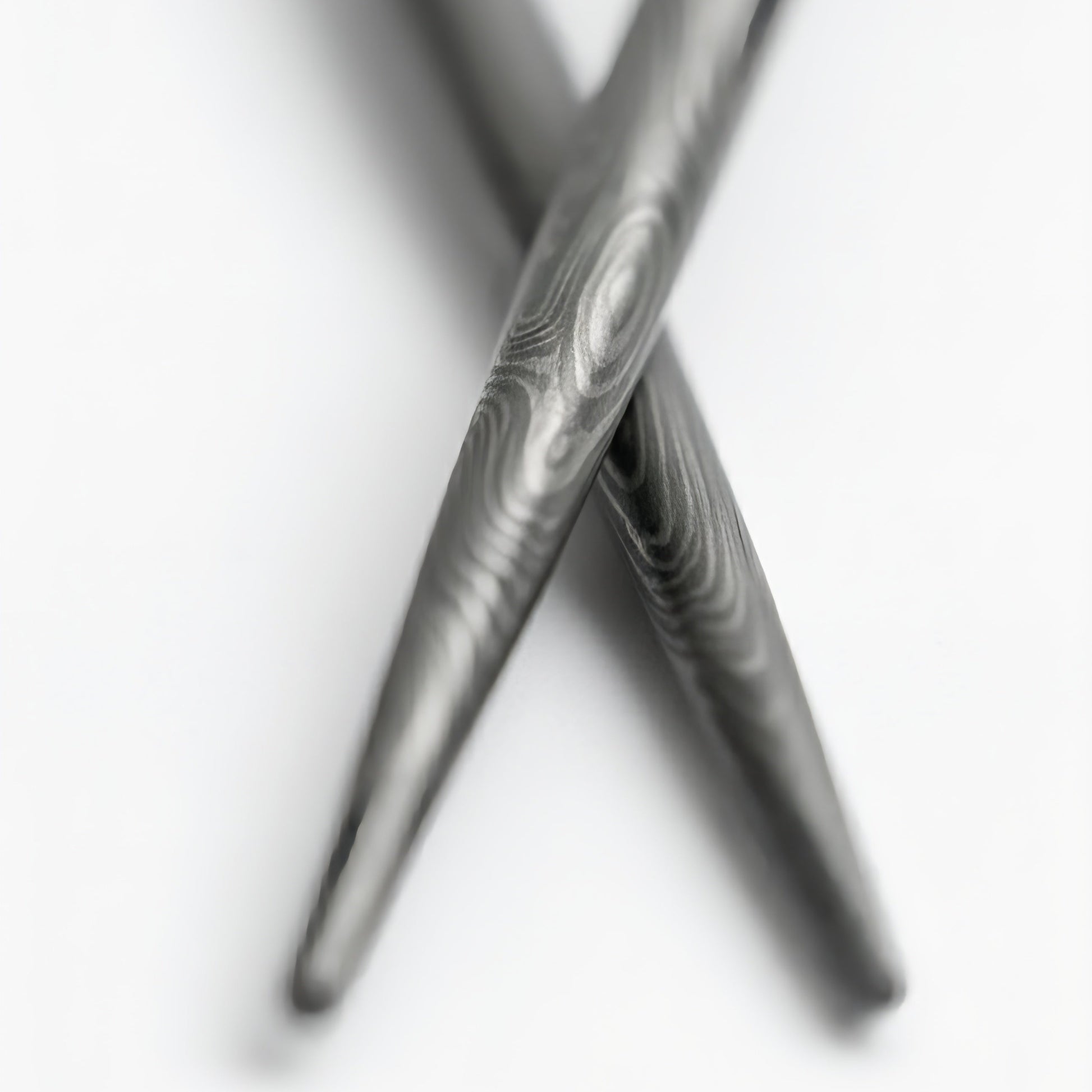 Close-up of two crossed damascus chopsticks