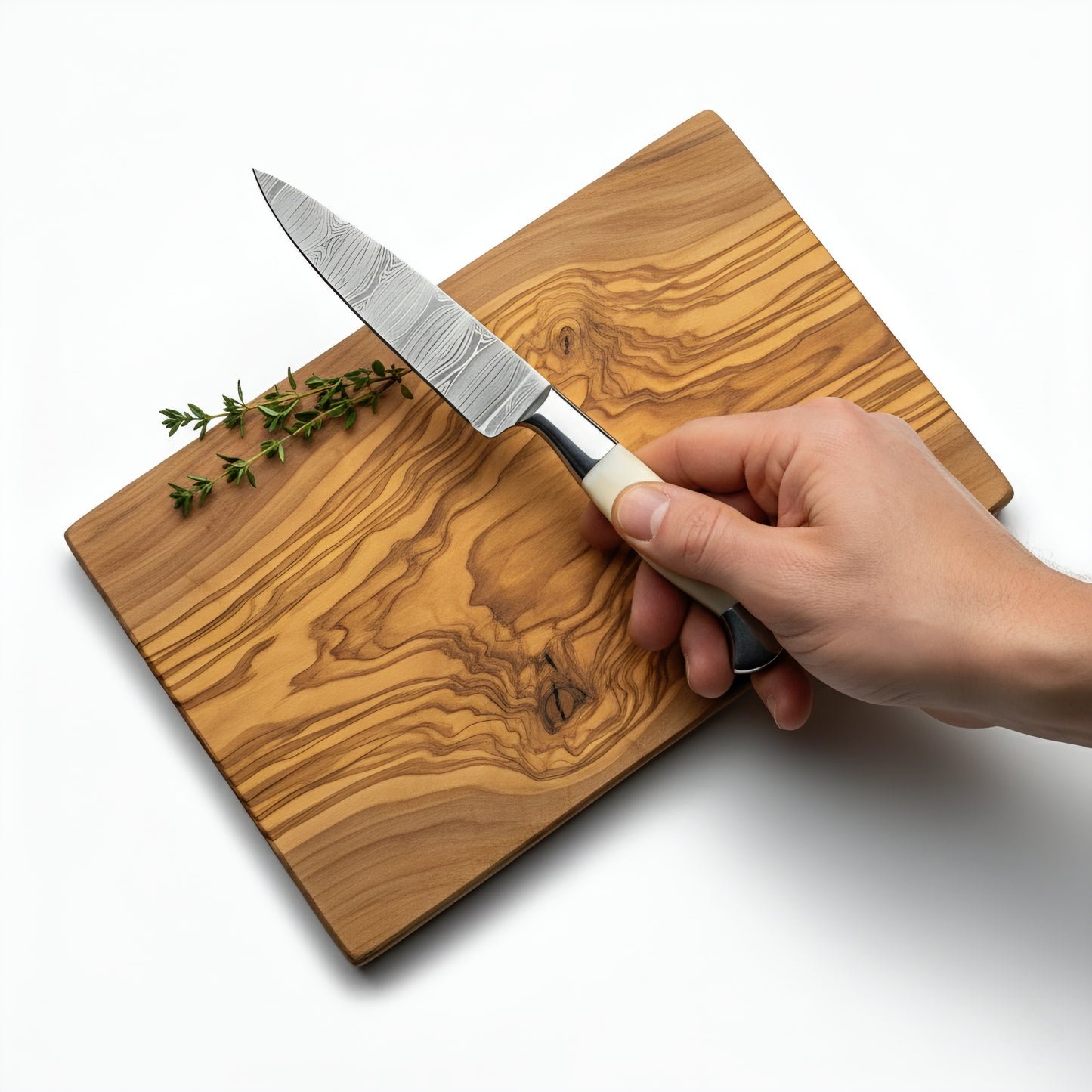 Hand holding a knife on a wooden cutting board with herbs