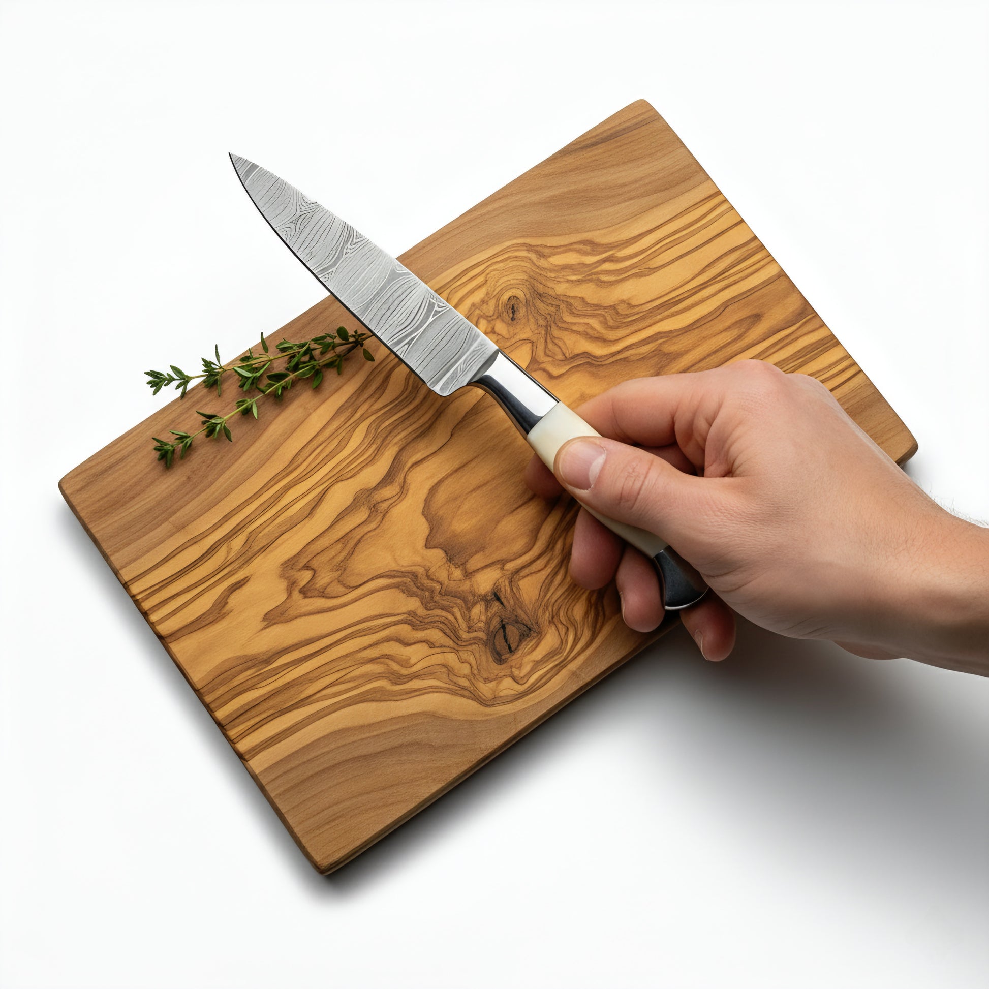 Hand holding a knife on a wooden cutting board with herbs