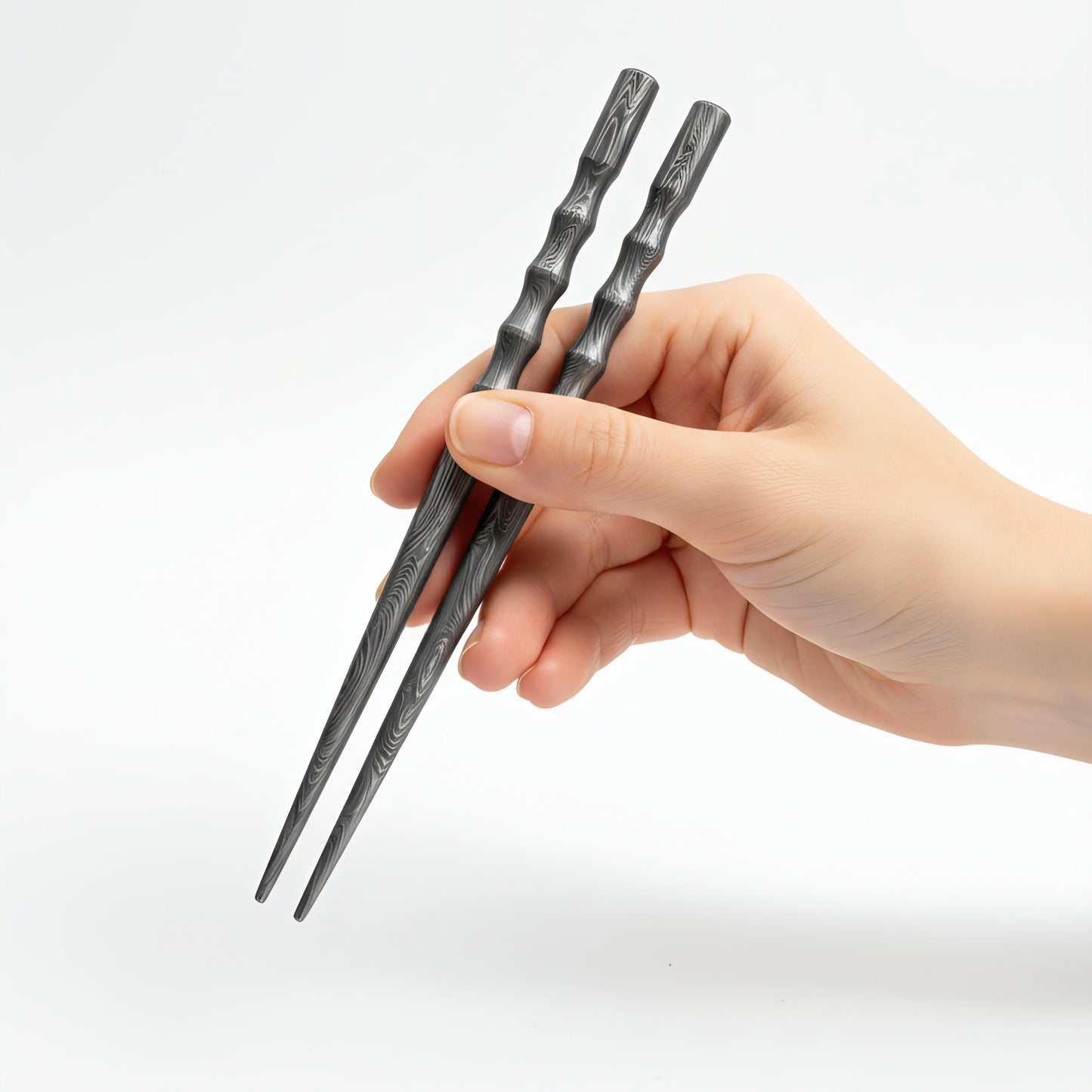 Hand holding a pair of black chopsticks damascus chopstick