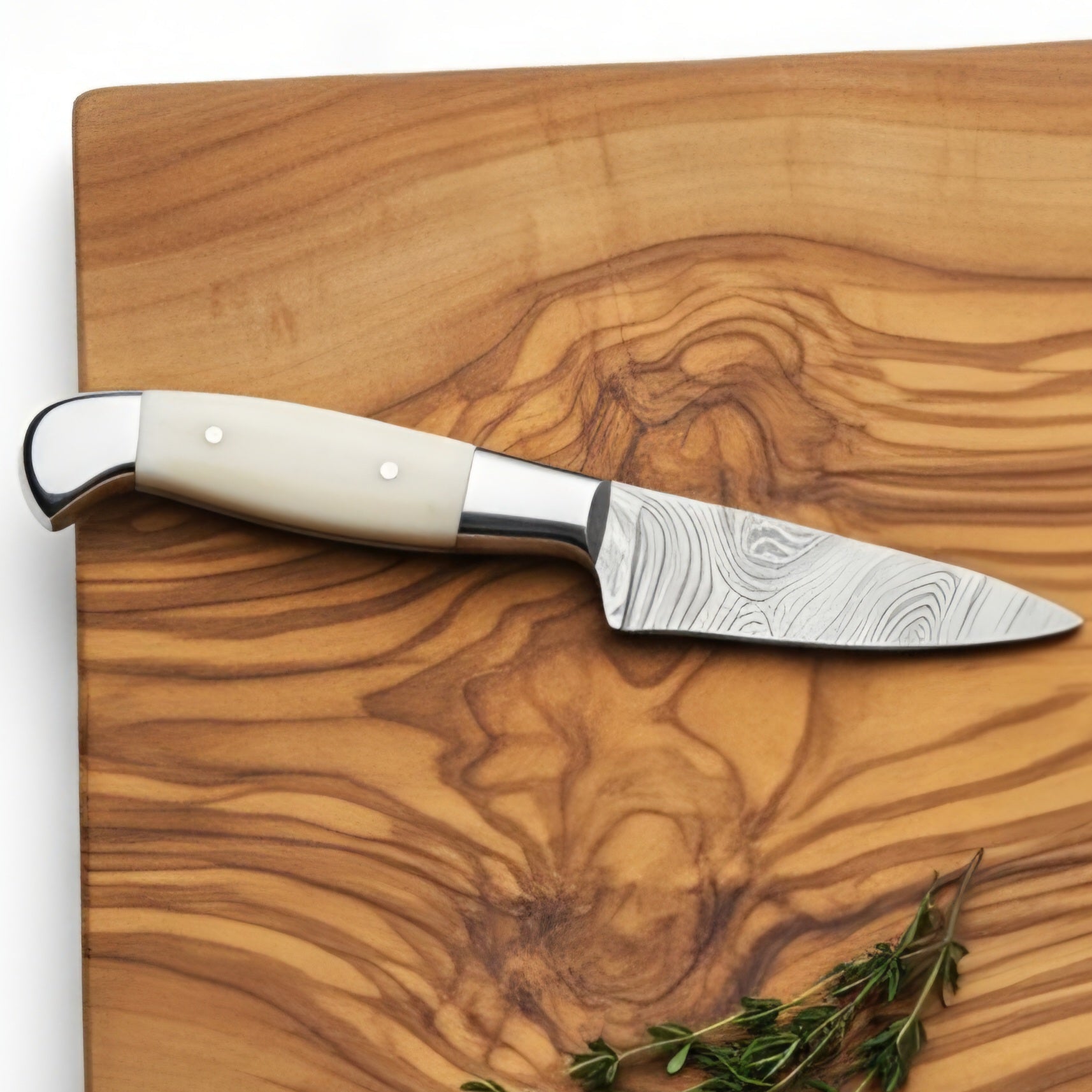 Knife with a wooden handle on a wooden cutting board with fresh herbs.