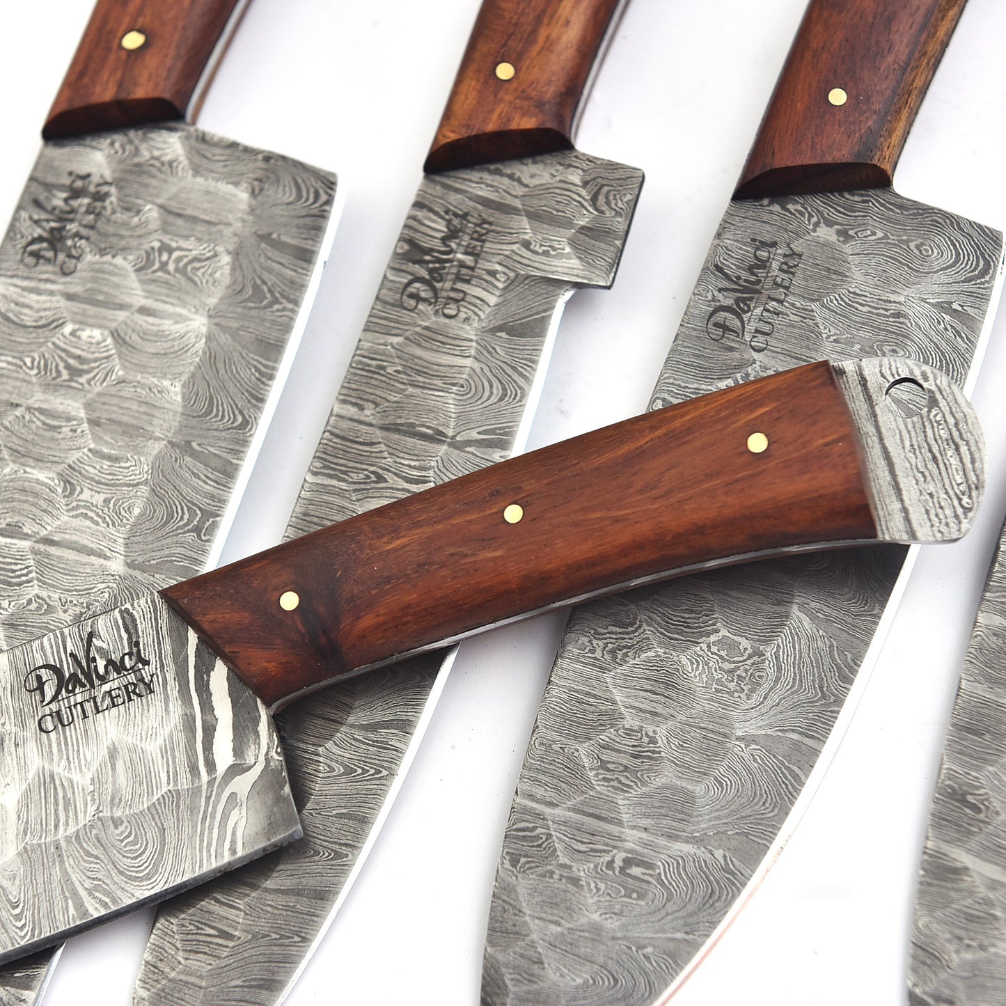 Set of four Damascus steel knives with wooden handles on a white background