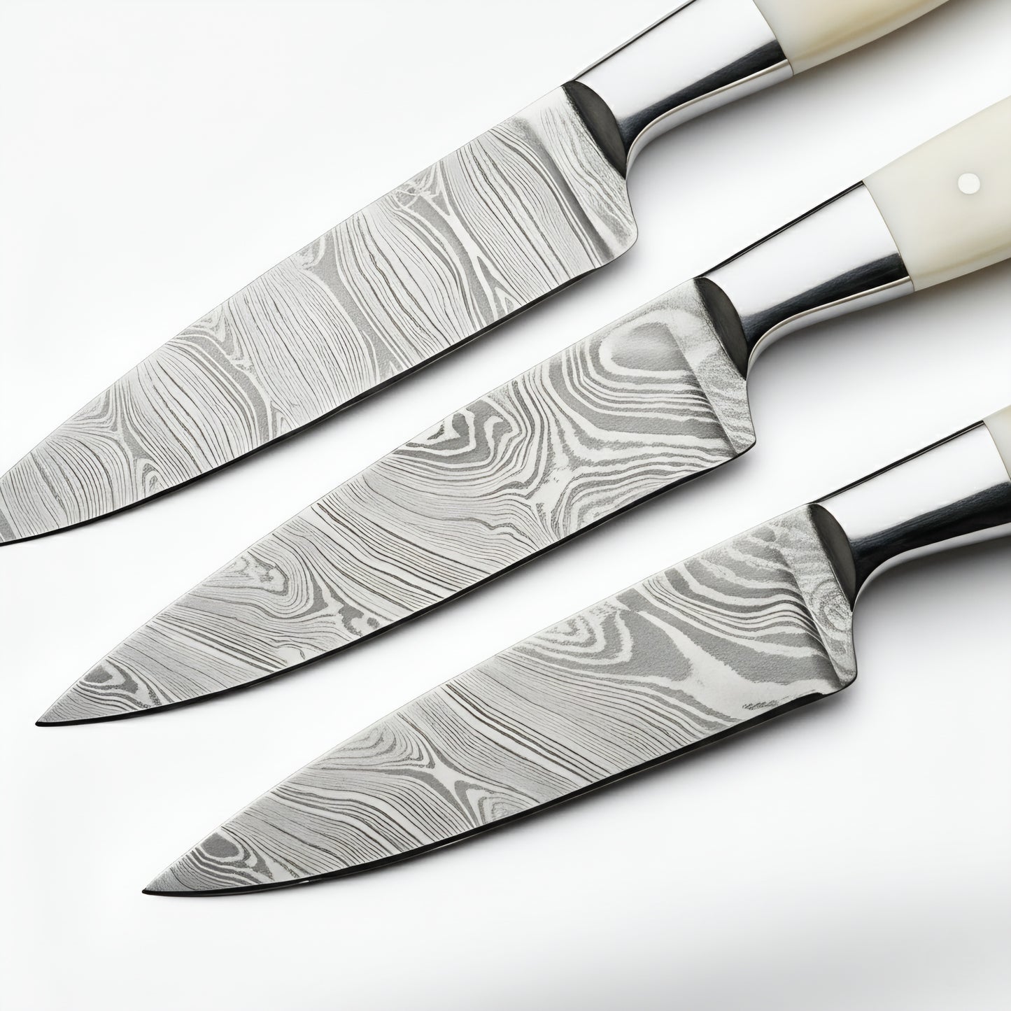 Set of three damascus steel kitchen knives on a white background