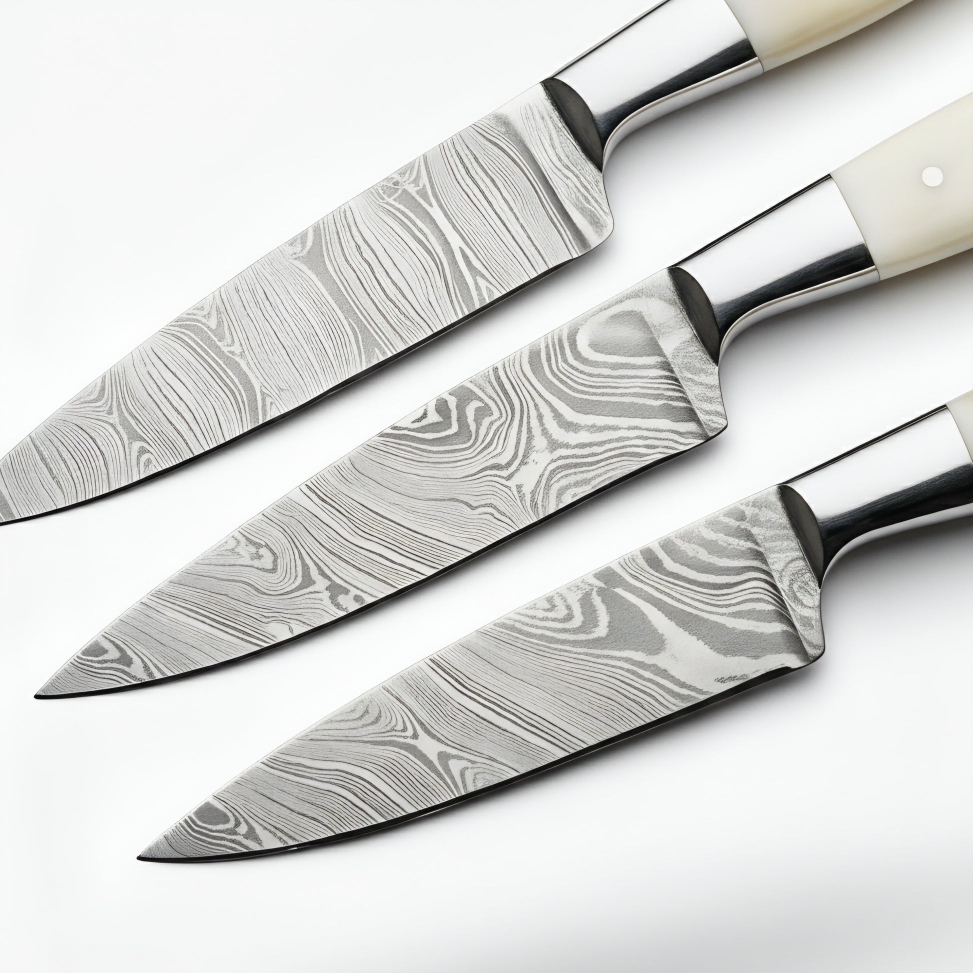 Set of three damascus steel kitchen knives on a white background