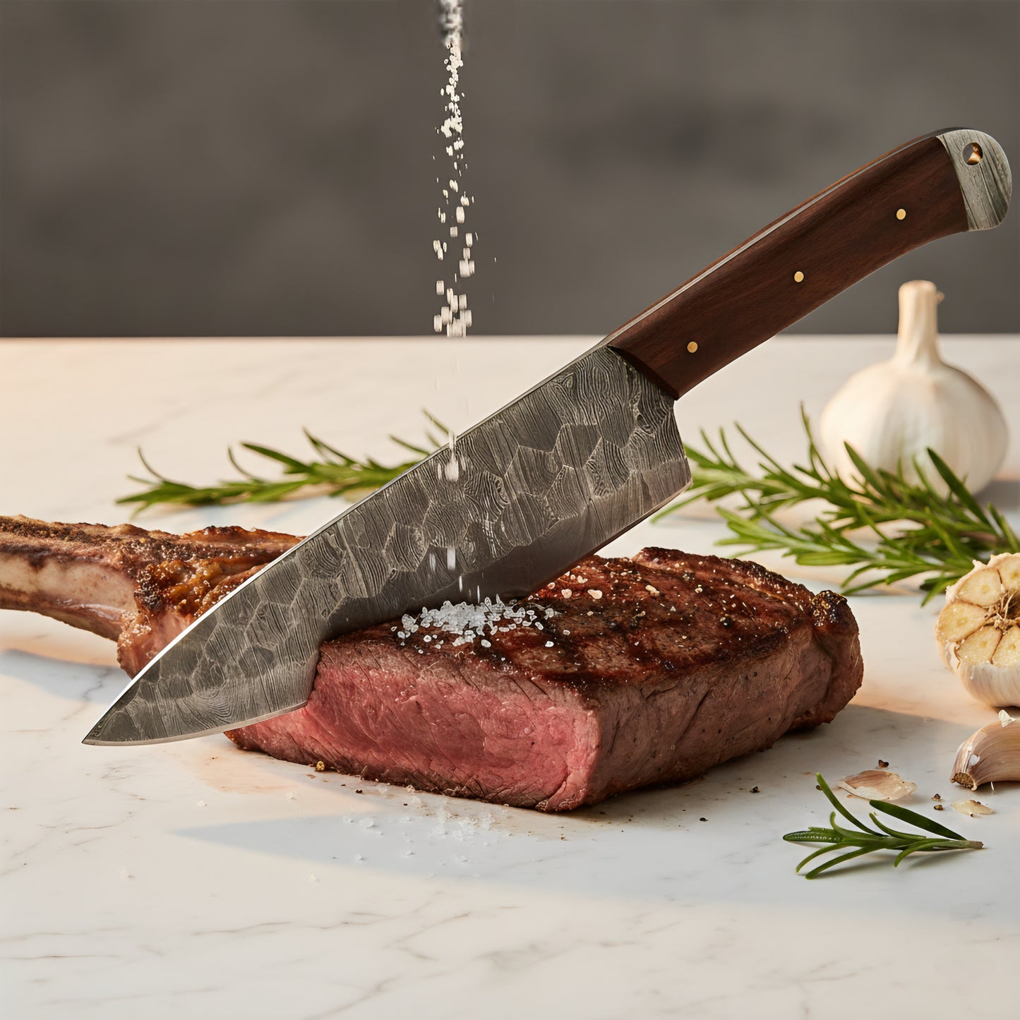 Steak being cut with a knife on a marble surface, surrounded by rosemary and garlic.