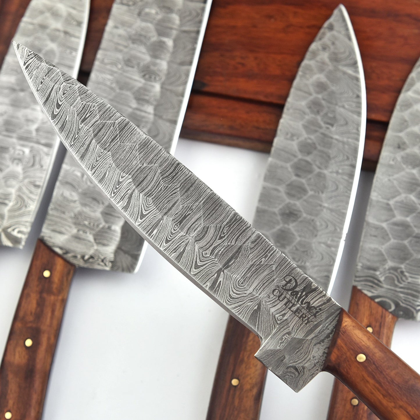 Set of Damascus steel knives with wooden handles on a white background