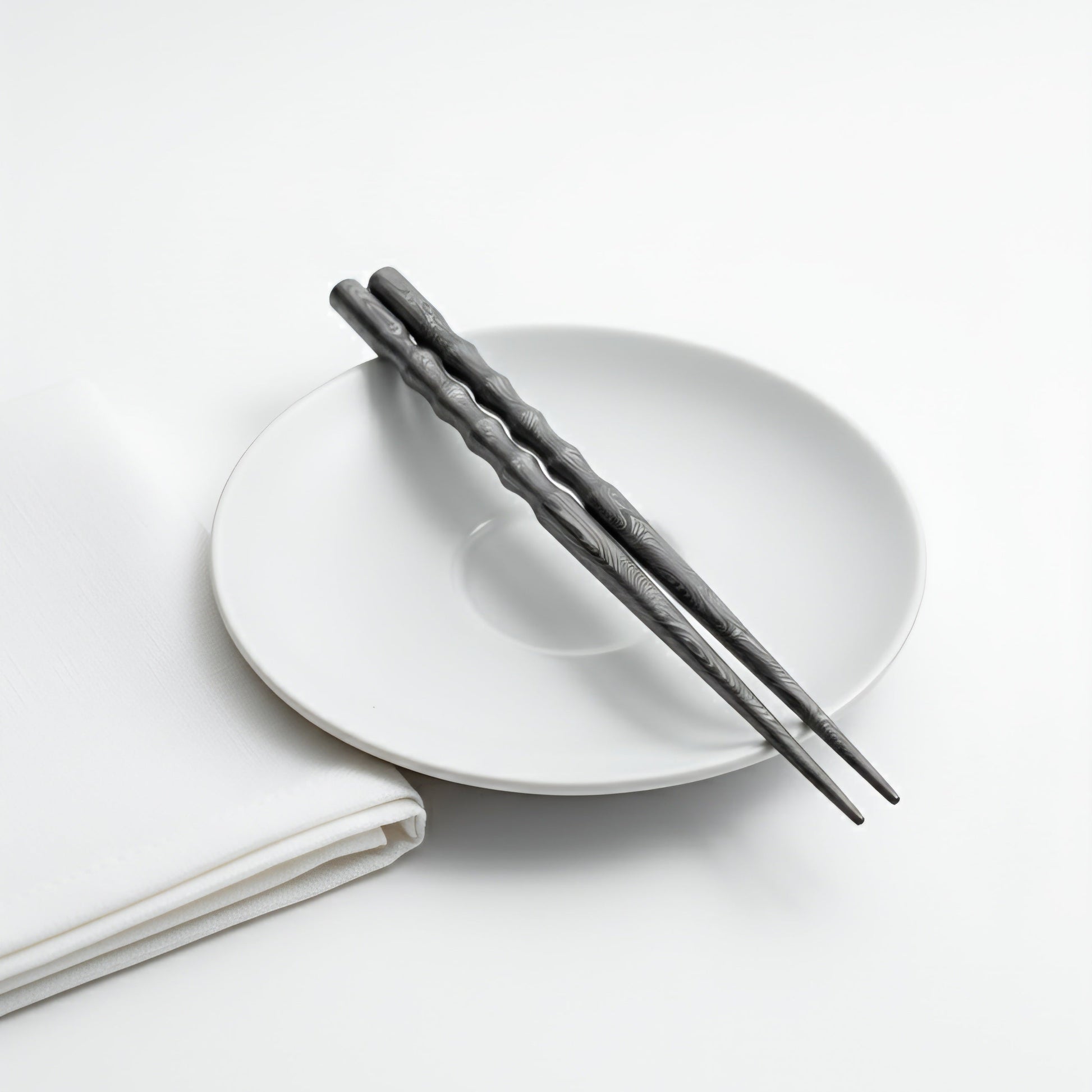 White plate with black chopsticks on a white background