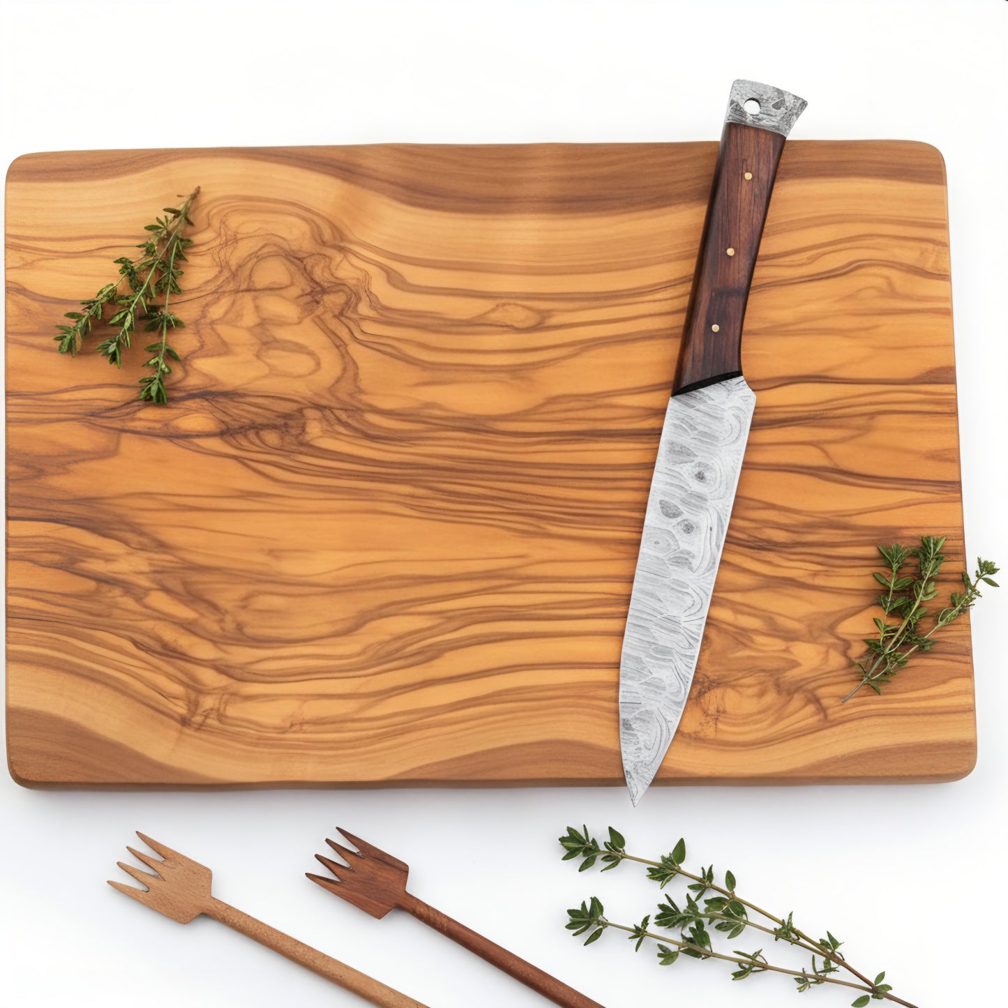 Wooden cutting board with a knife, herbs, and wooden utensils on a white background