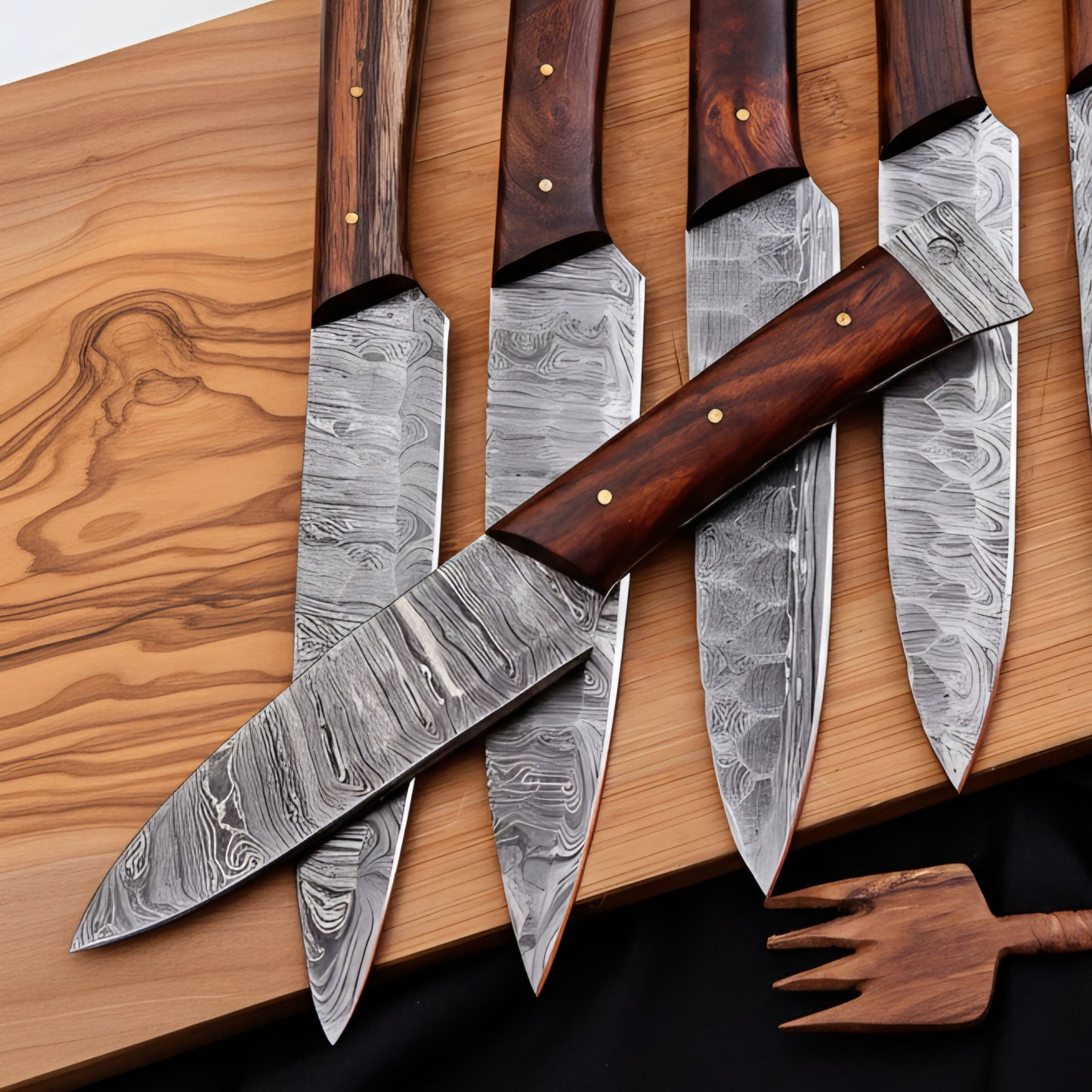 Set of Damascus steel knives with wooden handles on a wooden surface