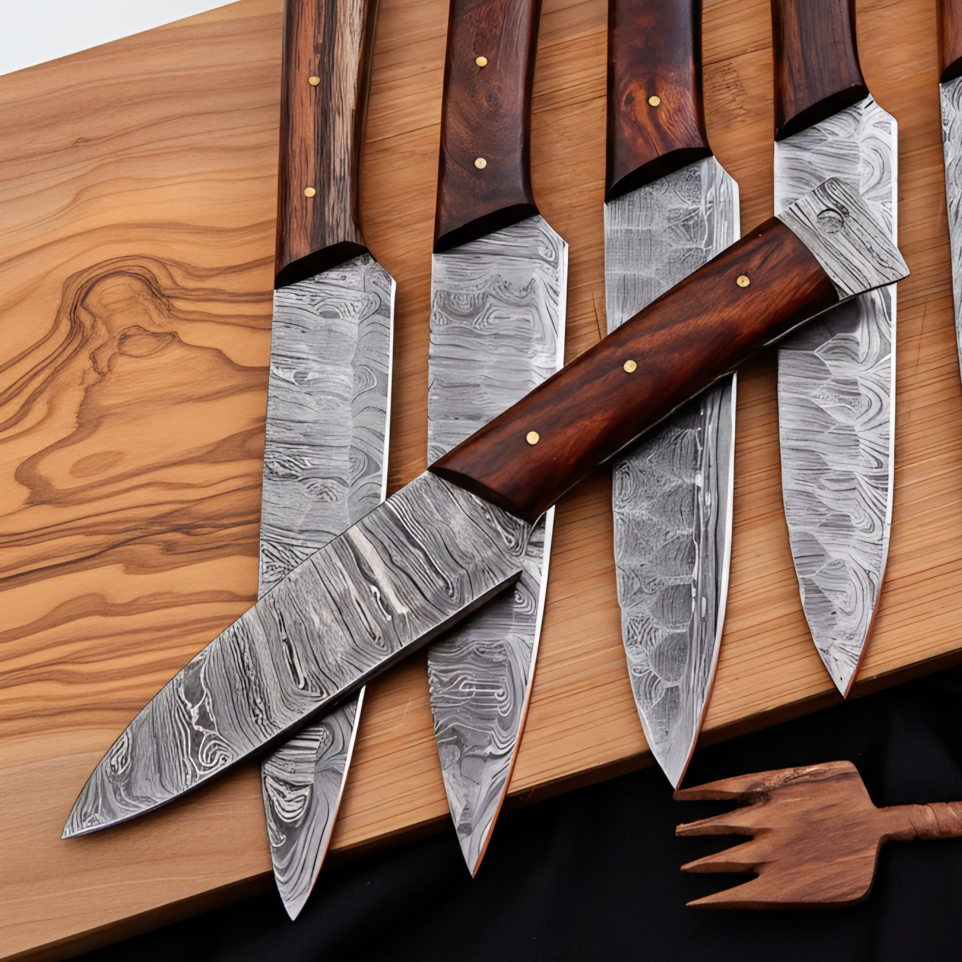 Set of Damascus steel knives with wooden handles on a wooden surface