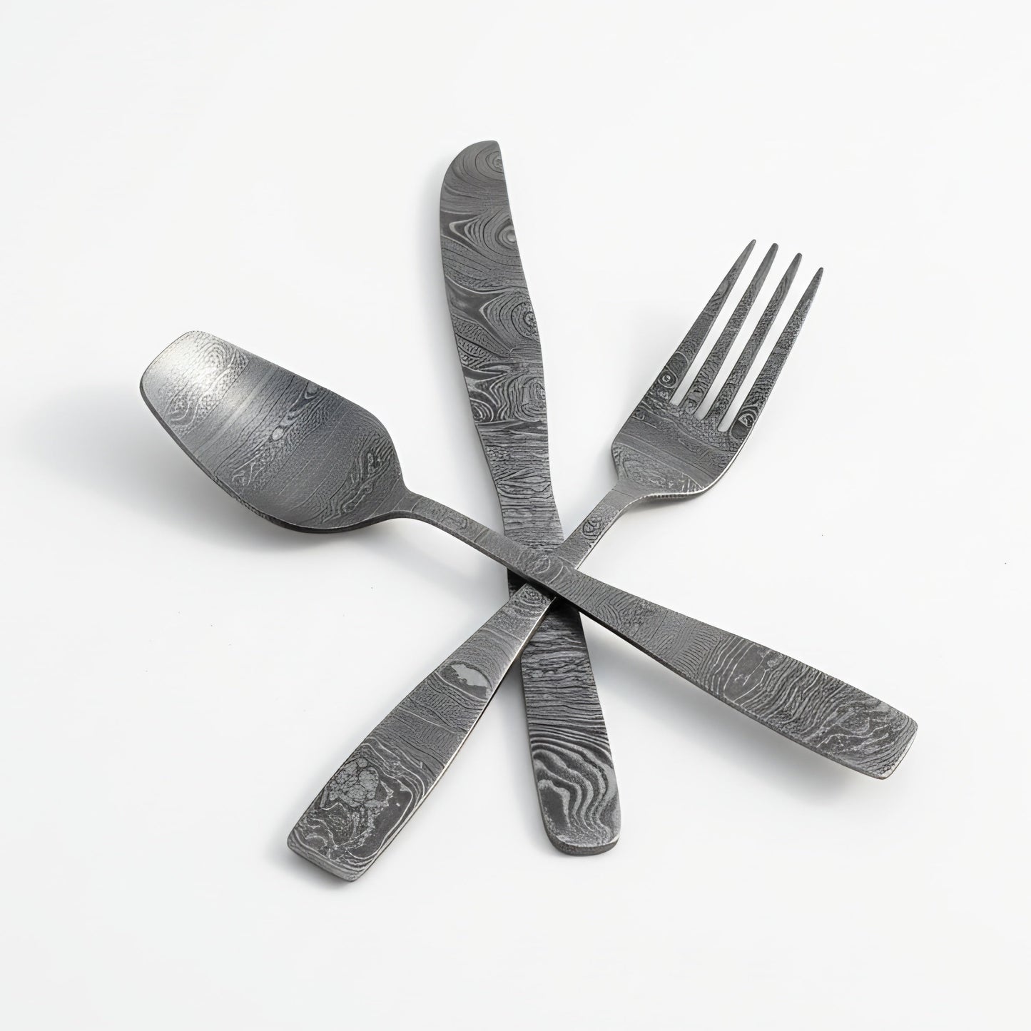 Damascus cutlery set Set of silver cutlery with embossed patterns on a white background