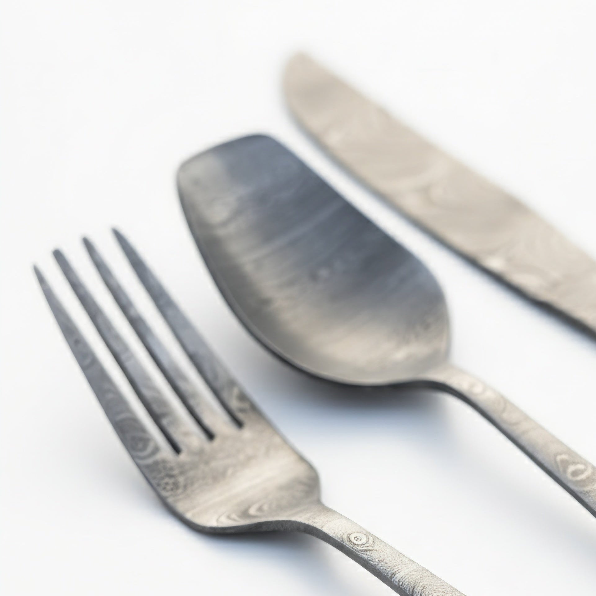 Set of silverware including a fork, spoon, and knife on a white background Damascus cutlery set
