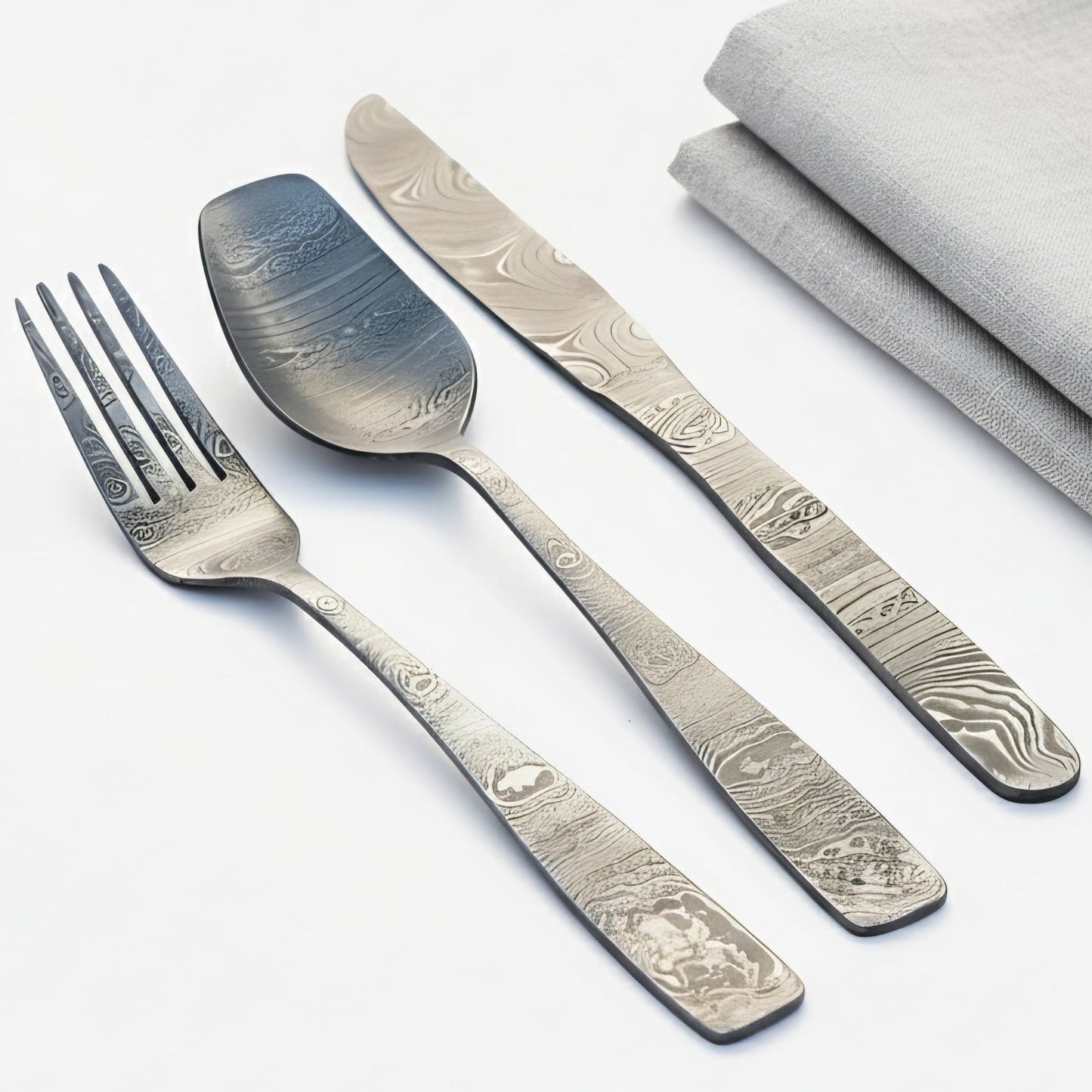 Silver cutlery set with engraved patterns on a white background Damascus cutlery set