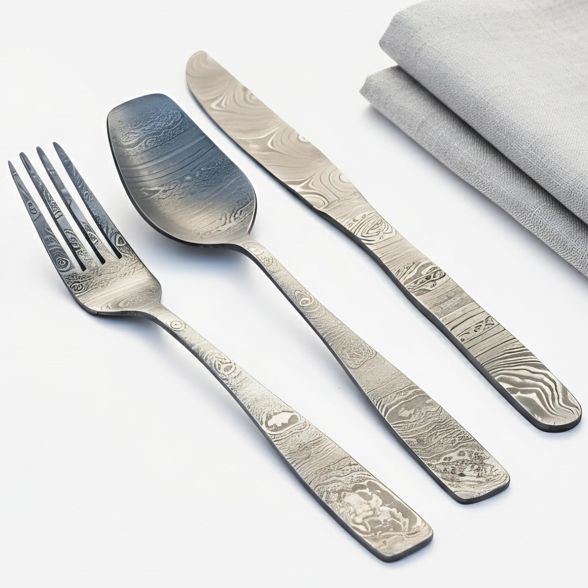 Silver cutlery set with engraved patterns on a white background Damascus cutlery set
