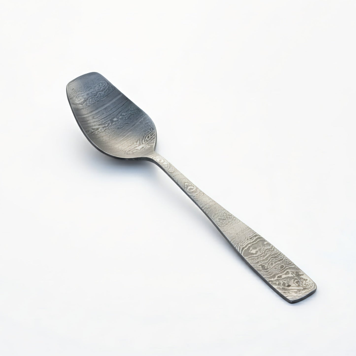 Silver spoon with engraved design on a white background Damascus cutlery set
