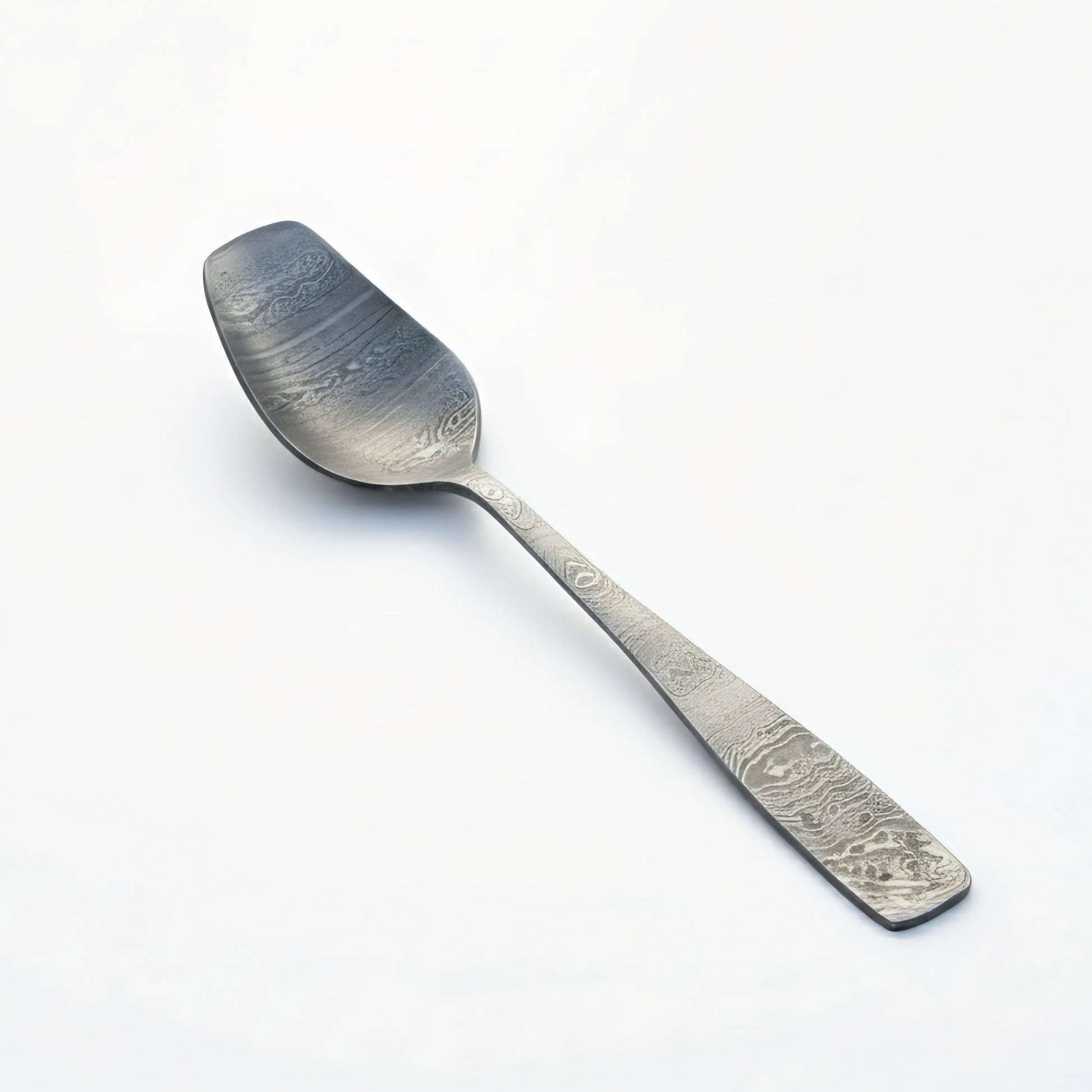 Silver spoon with engraved design on a white background Damascus cutlery set