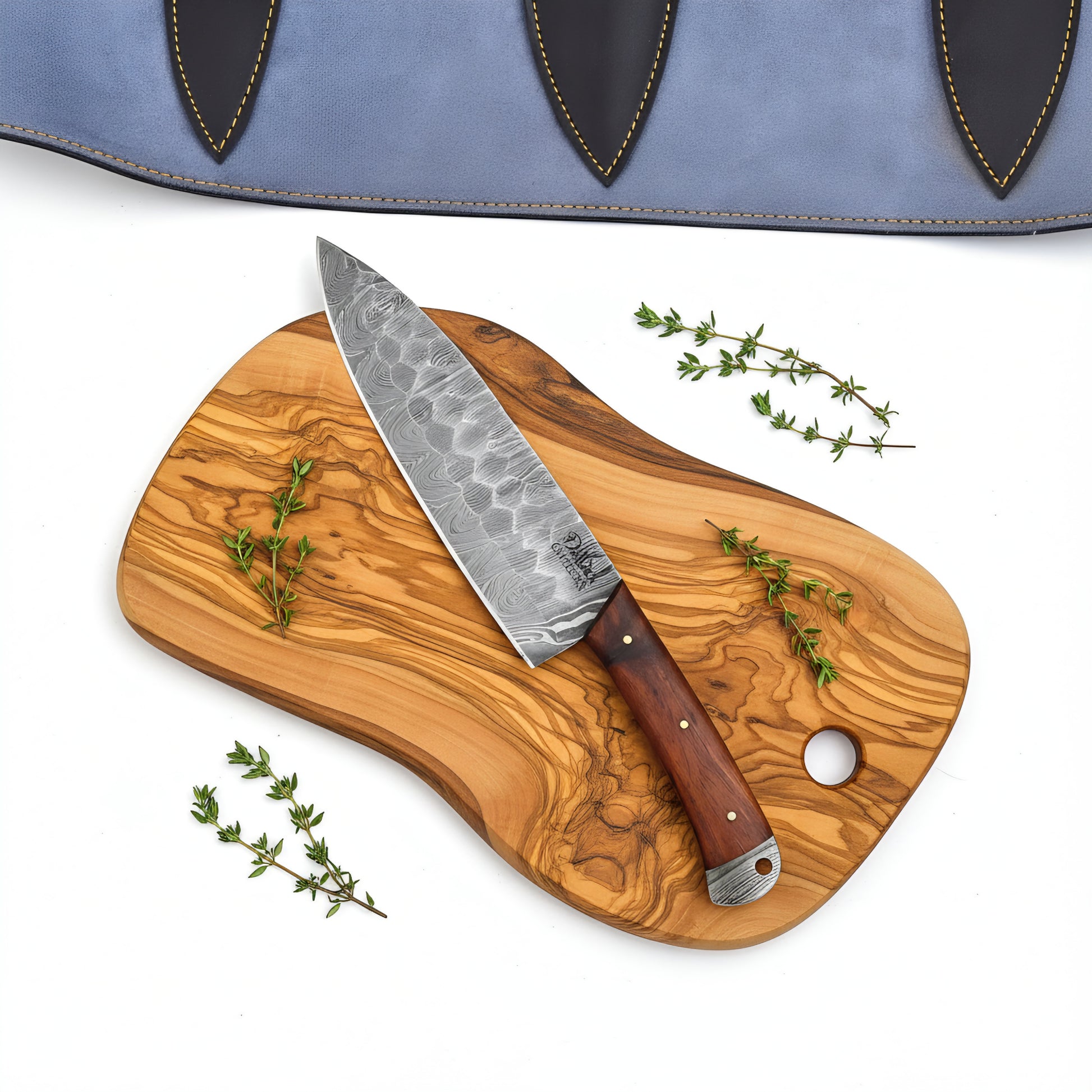 Wooden cutting board with a chef's knife and thyme on a white background