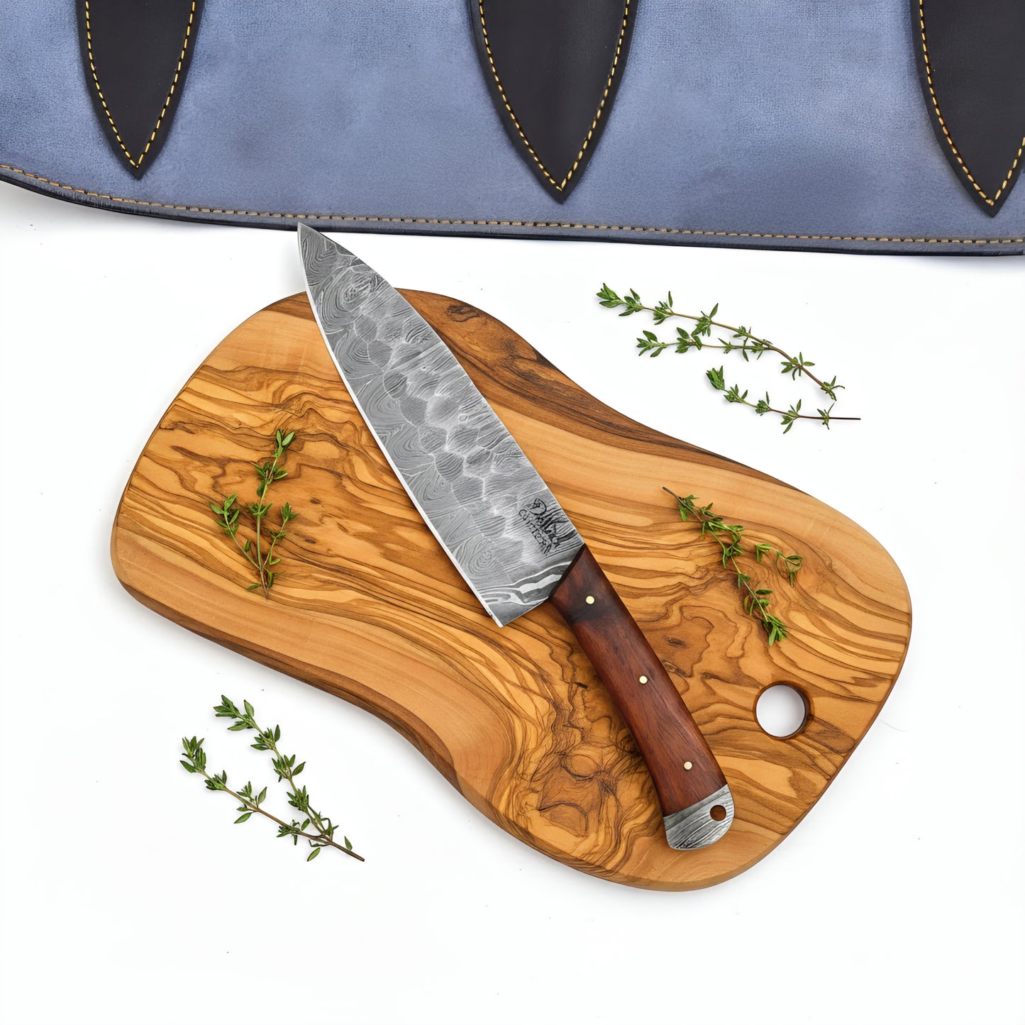 Wooden cutting board with a chef's knife and thyme on a white background